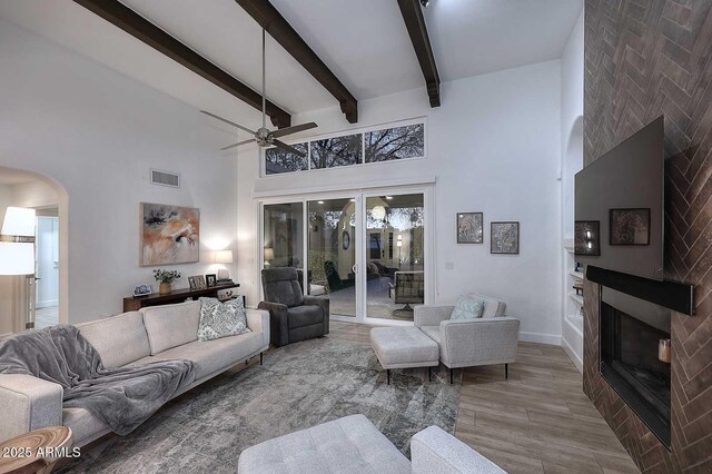 7596 N Via De La Siesta, Scottsdale, AZ 85258 - living room with a high ceiling, a ceiling fan, arched walkways, wood finished floors, and a glass covered fireplace