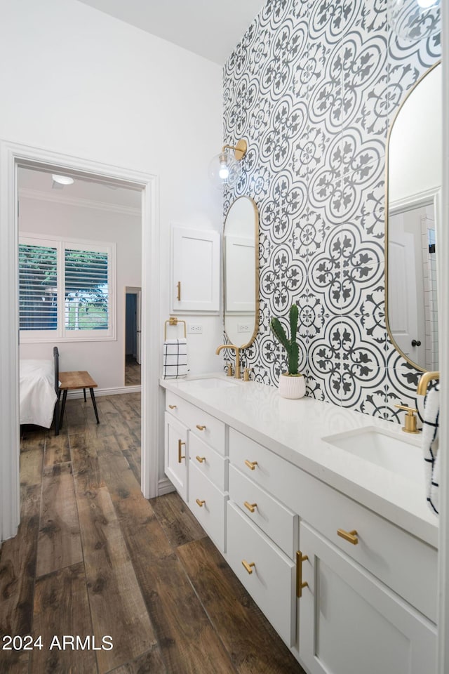 bathroom with double vanity, ornamental molding, a sink, and wood finished floors