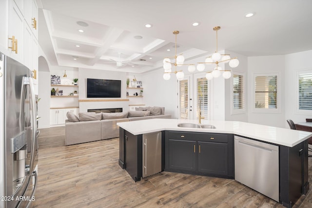 kitchen featuring open floor plan, stainless steel appliances, light wood-type flooring, and light countertops