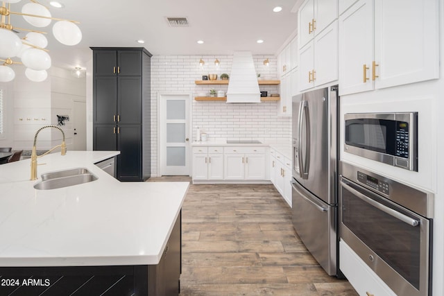 kitchen featuring wood finished floors, a sink, visible vents, appliances with stainless steel finishes, and backsplash