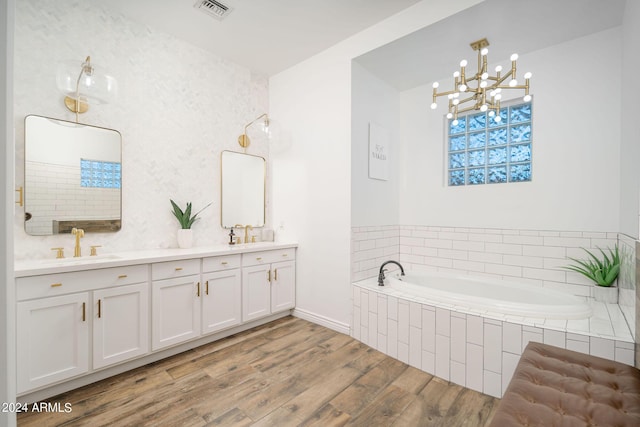 bathroom featuring a garden tub, wood finished floors, a sink, visible vents, and double vanity