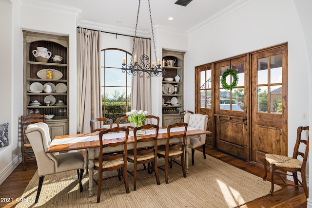 dining area with hardwood / wood-style floors, crown molding, and an inviting chandelier