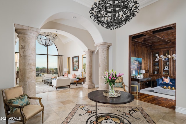 interior space featuring decorative columns, crown molding, wooden walls, and a notable chandelier