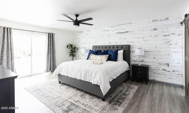 bedroom featuring wood-type flooring, wooden walls, access to exterior, and ceiling fan