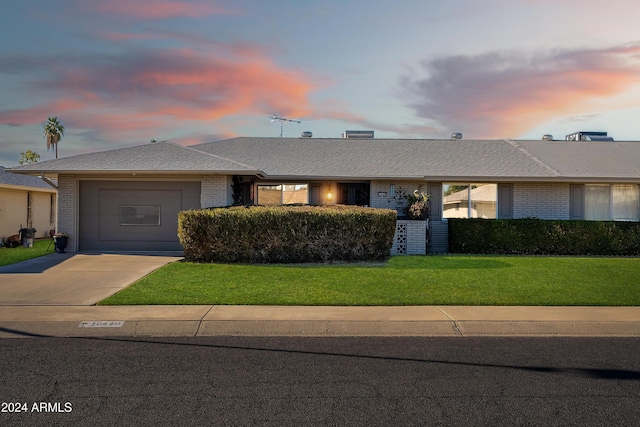 ranch-style house with a garage and a lawn