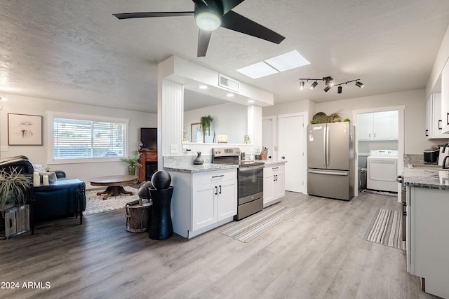 kitchen featuring a textured ceiling, stainless steel appliances, light hardwood / wood-style flooring, white cabinets, and washer / clothes dryer