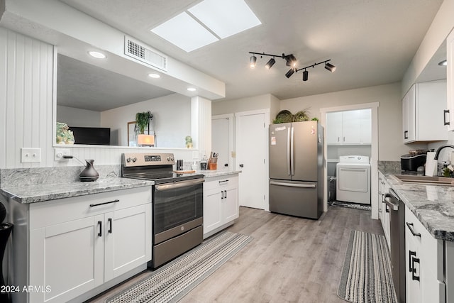 kitchen featuring stainless steel appliances, white cabinetry, washer / clothes dryer, and sink