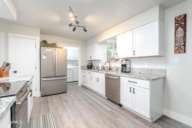 kitchen featuring sink, light hardwood / wood-style flooring, independent washer and dryer, white cabinets, and appliances with stainless steel finishes