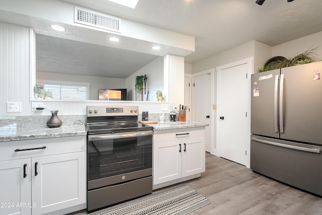 kitchen featuring light wood-type flooring, white cabinetry, light stone counters, and appliances with stainless steel finishes