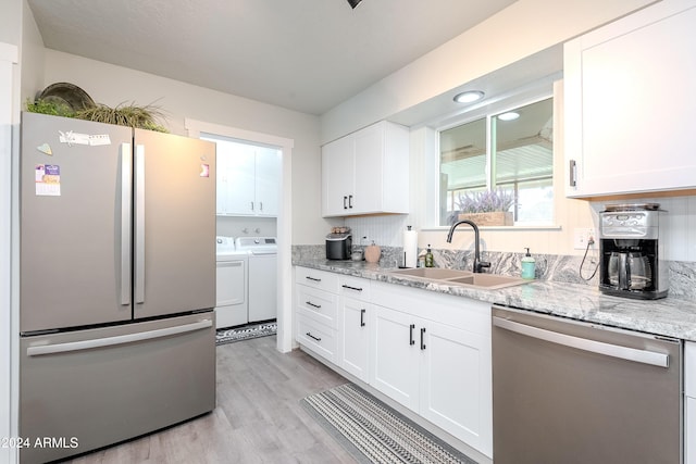 kitchen featuring white cabinets, independent washer and dryer, sink, and appliances with stainless steel finishes