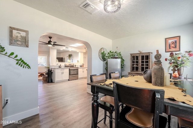 dining area featuring ceiling fan, light hardwood / wood-style floors, and a textured ceiling