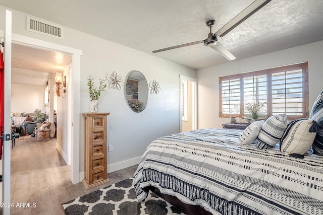 bedroom with ceiling fan, a textured ceiling, and light wood-type flooring