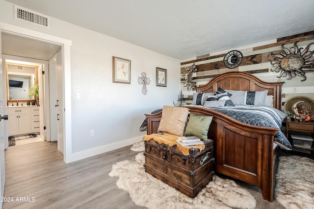 bedroom featuring ensuite bath, sink, and light hardwood / wood-style floors