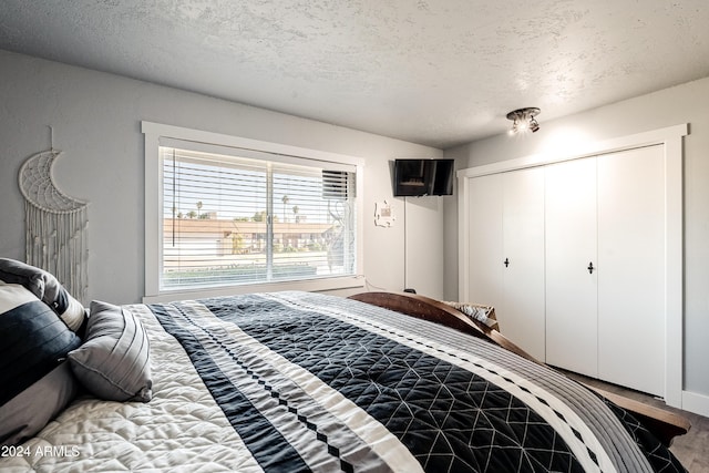 bedroom featuring hardwood / wood-style floors, a textured ceiling, and a closet