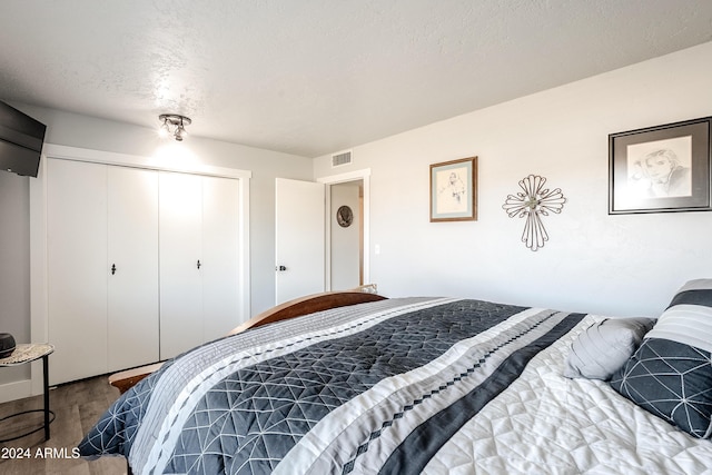 bedroom featuring wood-type flooring, a textured ceiling, and a closet