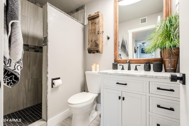 bathroom featuring tiled shower, vanity, and toilet