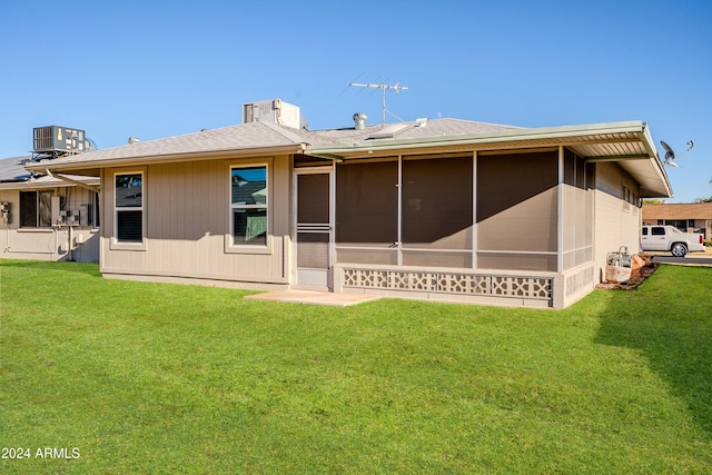 rear view of house featuring a lawn, a sunroom, and central AC