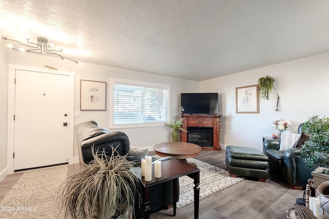 living room with hardwood / wood-style flooring, a textured ceiling, and an inviting chandelier