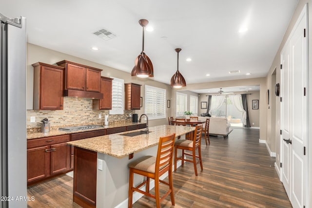 kitchen with decorative light fixtures, a kitchen island with sink, dark hardwood / wood-style floors, and sink