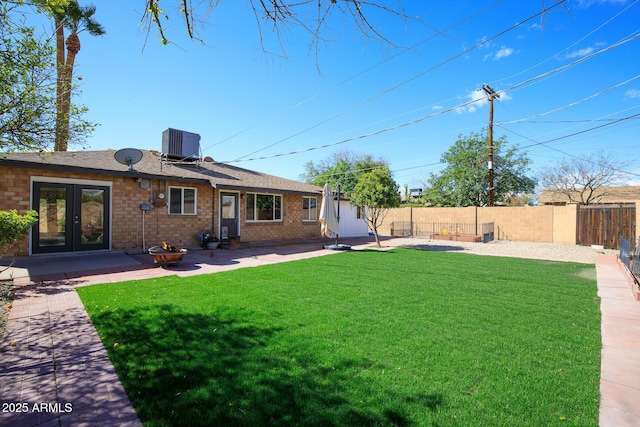 view of yard with french doors, central AC, a fenced backyard, and a patio area