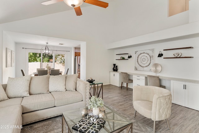 living room featuring wood-type flooring, ceiling fan with notable chandelier, and vaulted ceiling