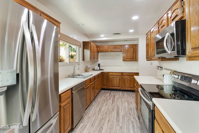 kitchen with sink, stainless steel appliances, and light wood-type flooring