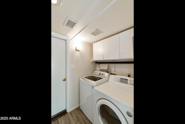 laundry room featuring cabinets, light hardwood / wood-style flooring, and washing machine and clothes dryer