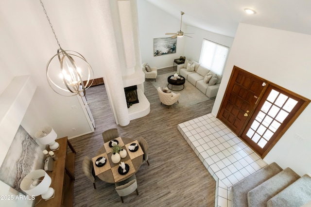 living room featuring ceiling fan with notable chandelier, a large fireplace, and a towering ceiling