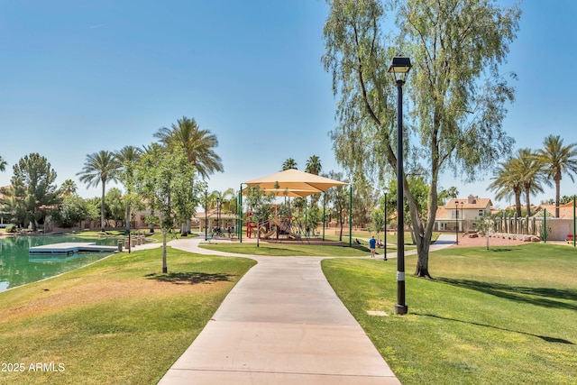 view of community featuring a playground, a yard, and a water view