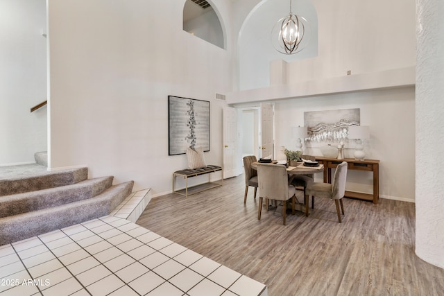 dining area featuring a high ceiling, an inviting chandelier, and wood-type flooring