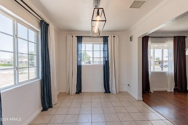 unfurnished dining area featuring light tile patterned floors, a wealth of natural light, and ornamental molding