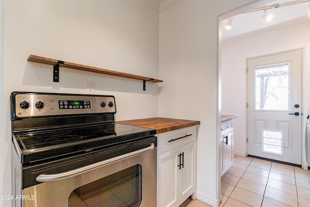 kitchen featuring white cabinets, wooden counters, stainless steel range with electric stovetop, light tile patterned floors, and ornamental molding