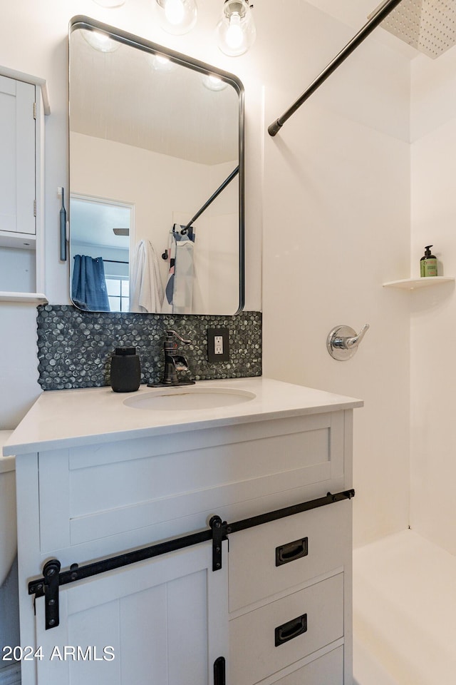 bathroom with decorative backsplash, vanity, and walk in shower