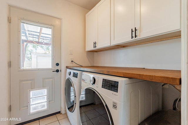 washroom featuring cabinets, light tile patterned floors, and washing machine and clothes dryer