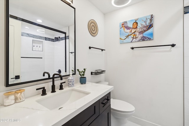 bathroom with vanity, toilet, and a tile shower