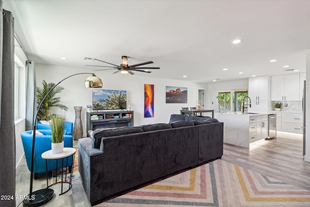 living room featuring sink, light wood-type flooring, and ceiling fan