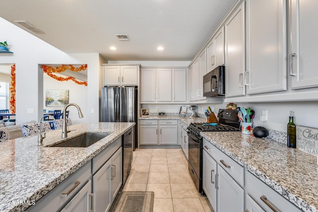 kitchen featuring light stone countertops, sink, light tile patterned floors, and black appliances