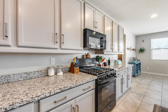 kitchen featuring light stone counters, light tile patterned floors, and black appliances