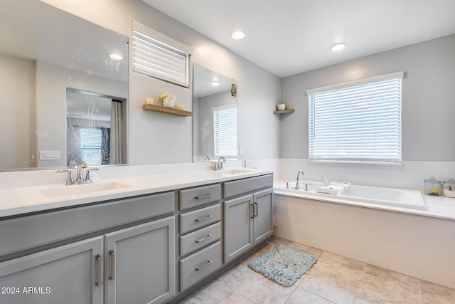 bathroom with tile patterned floors, vanity, a washtub, and a wealth of natural light