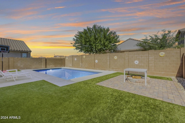 pool at dusk featuring a yard and a patio