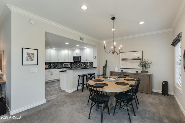 carpeted dining area featuring crown molding, a chandelier, and sink