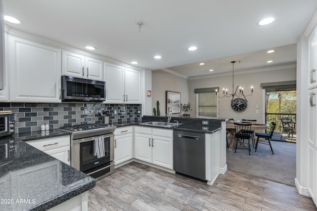 kitchen featuring sink, kitchen peninsula, white cabinets, and appliances with stainless steel finishes