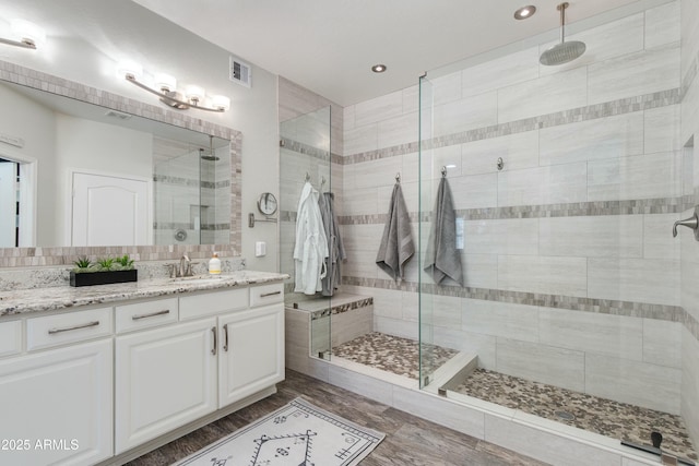 bathroom with hardwood / wood-style flooring, vanity, and a tile shower