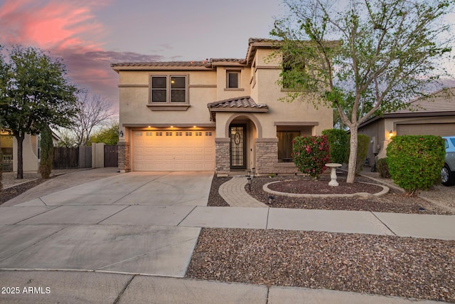 mediterranean / spanish-style home featuring fence, stucco siding, concrete driveway, stone siding, and a tile roof