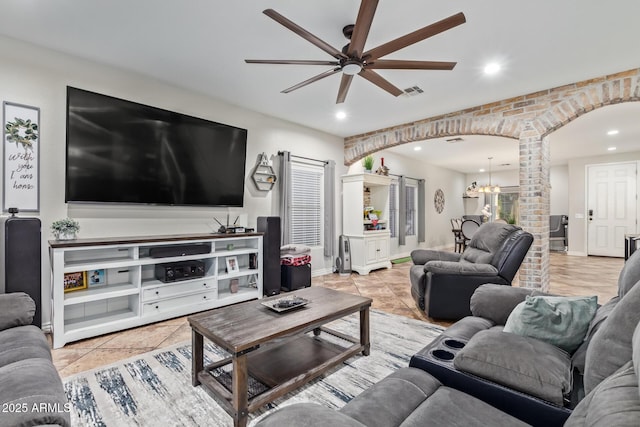 living area featuring visible vents, ceiling fan with notable chandelier, recessed lighting, arched walkways, and decorative columns