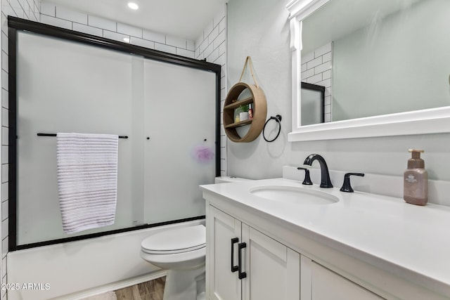 full bathroom featuring bath / shower combo with glass door, toilet, recessed lighting, wood finished floors, and vanity