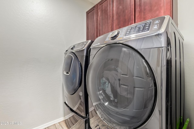 laundry area featuring separate washer and dryer, cabinet space, and baseboards