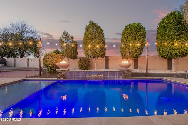 pool at dusk featuring a fenced in pool and a fenced backyard