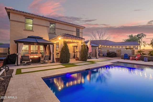 view of pool featuring a gazebo, a fire pit, a fenced backyard, and a patio area