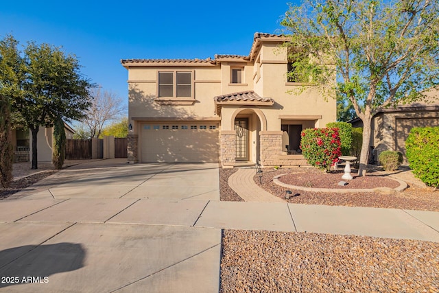 mediterranean / spanish home with fence, a tiled roof, stucco siding, stone siding, and driveway